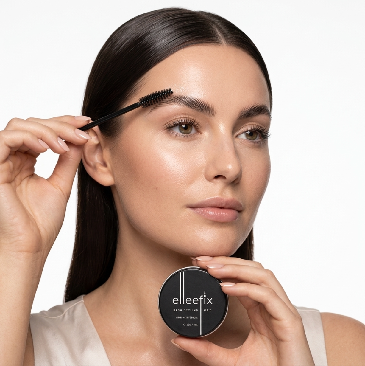 Brushing Elleefix Brow Styling Wax through eyebrow hairs using a spoolie for a lifted, brushed-up brow look.